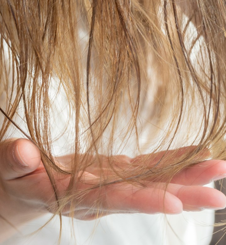 things to stop doing if you have thin hair universal: a closeup image of a woman examining her blonde hair